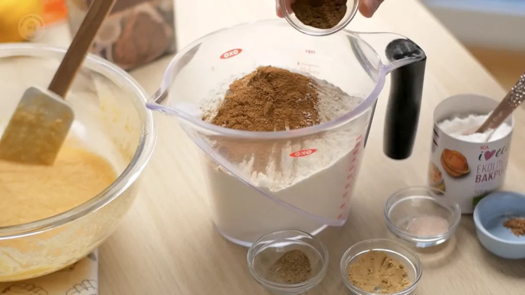 Dubenyje sumaišomi miltai ir prieskoniai, šalia esantys kiti ingredientai laukia naudojimo.